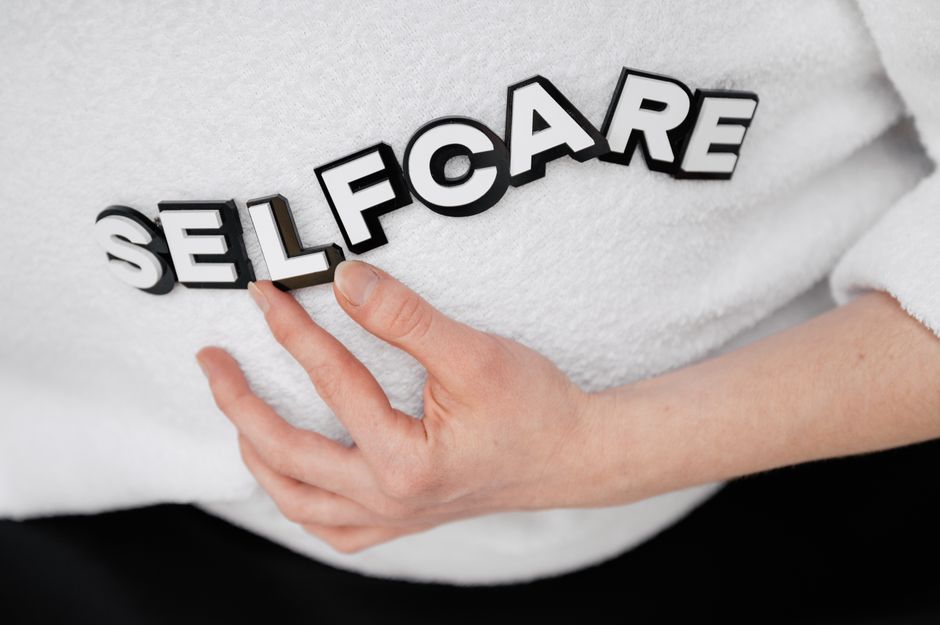 Close-up of a hand holding the word 'self-care' made with 3D letters on a white background.